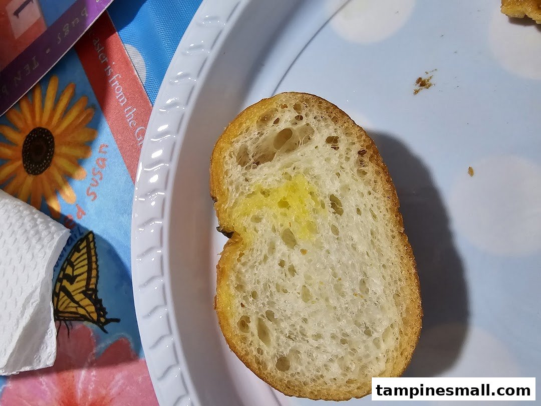 A close-up of a slice of golden-brown bread on a light blue plate, with a colorful placemat.