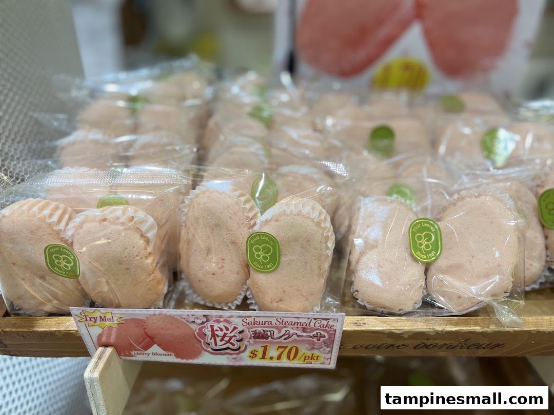 Rows of individually packaged pink Sakura Steamed Cakes displayed on a wooden shelf at Four Leaves.
