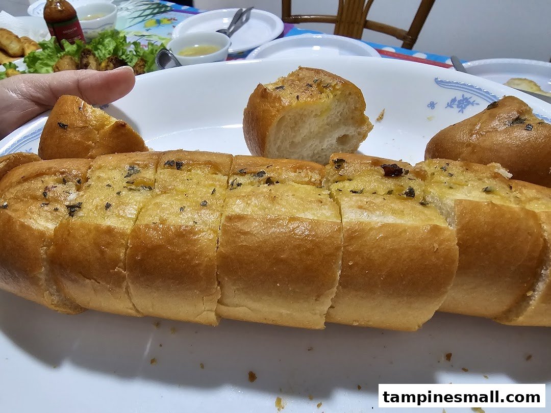 A close-up of a platter of golden-brown, sliced garlic bread with herbs, ready to be served.