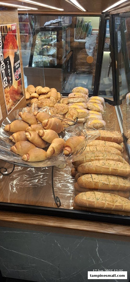A display case filled with freshly baked bread, pastries, and savory rolls at Four Leaves bakery.
