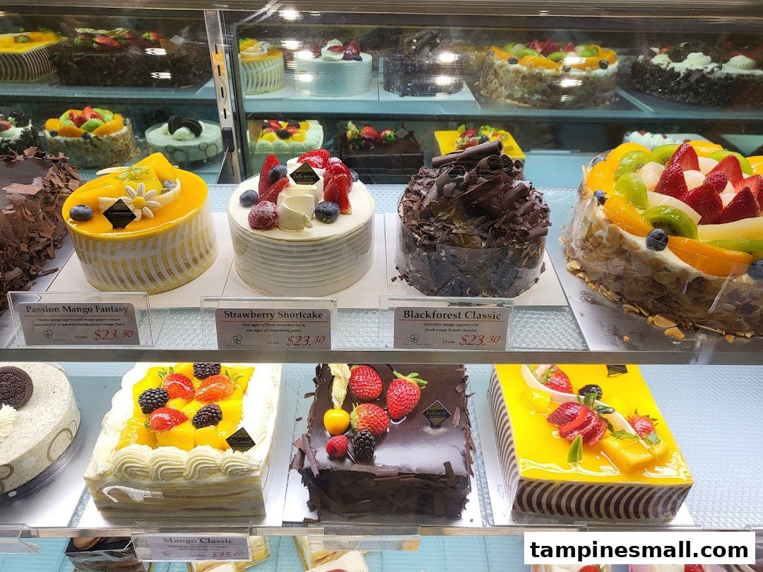 A vibrant display case showcasing a variety of beautifully decorated cakes and pastries at Four Leaves bakery.
