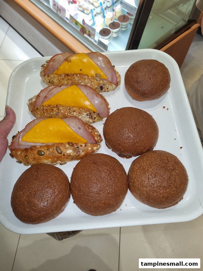 A tray of freshly baked ham and cheese sandwiches and dark buns from Four Leaves bakery.
