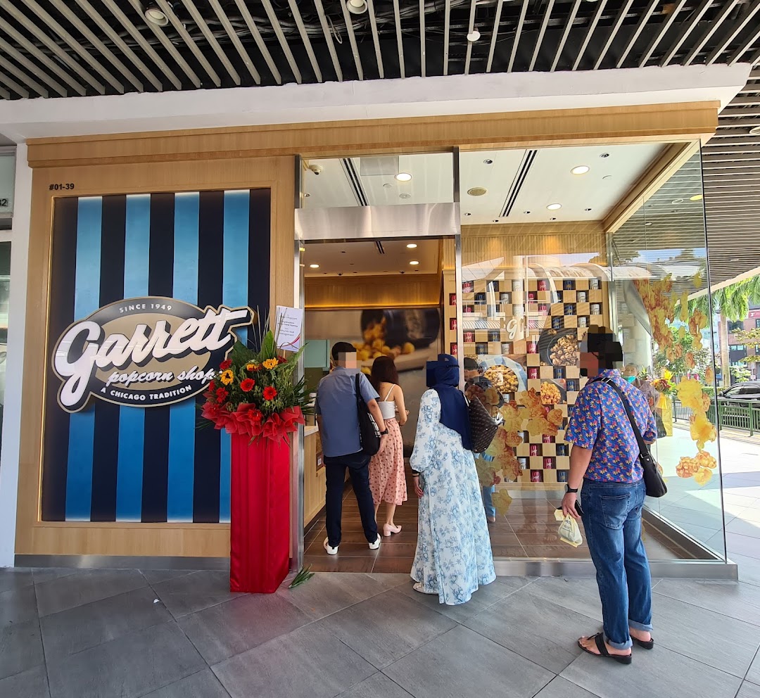 The vibrant storefront of Garrett Popcorn Shops at Tampines Mall, with customers entering.