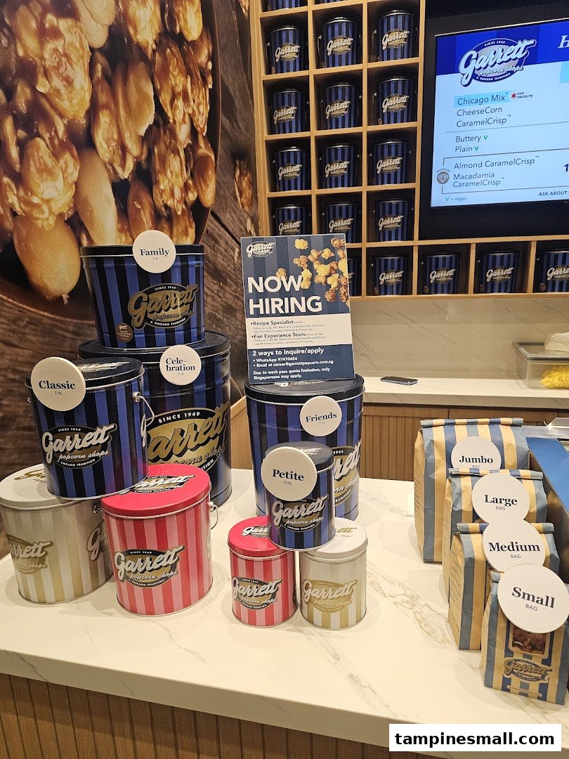 An interior view of Garrett Popcorn Shops, showcasing various popcorn tins, bags, and a digital menu.