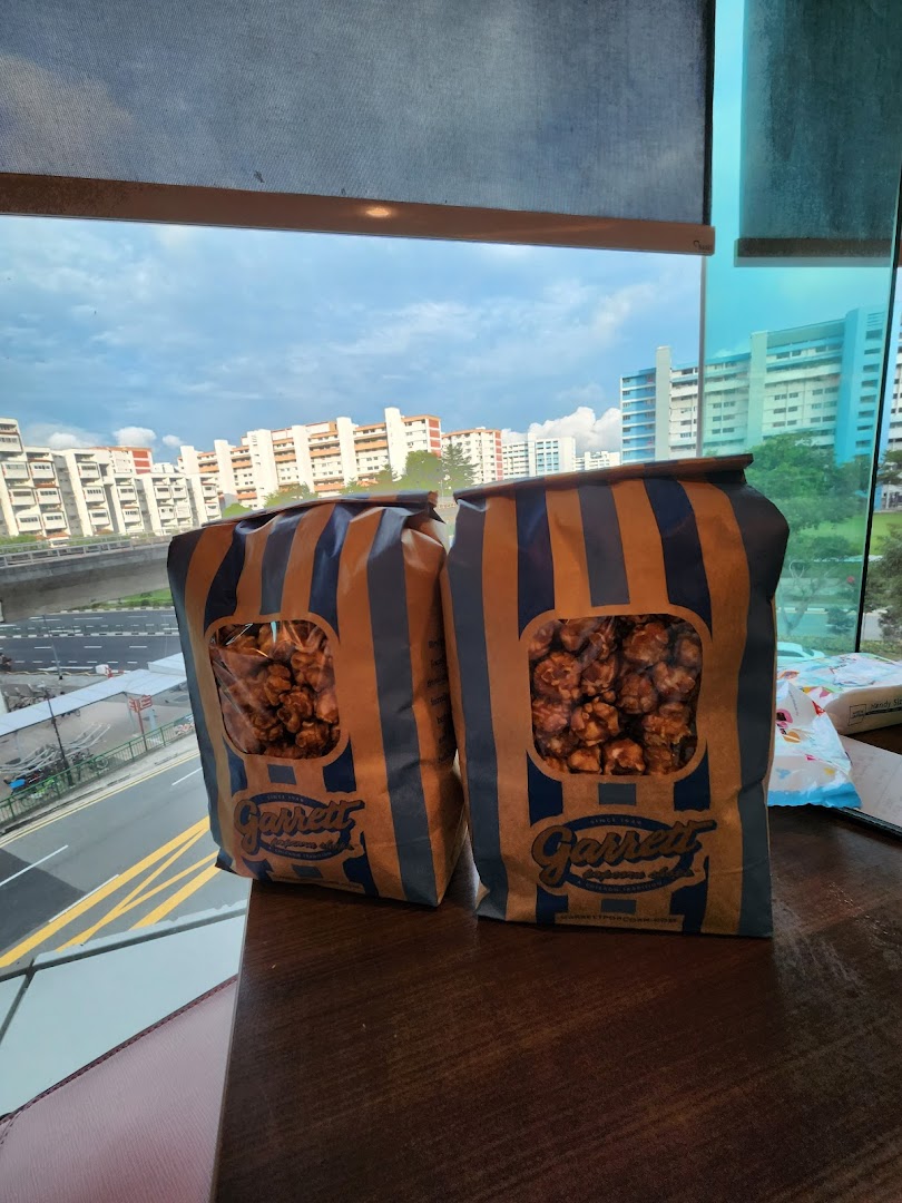 Two bags of Garrett Popcorn on a table with a city view from a window.