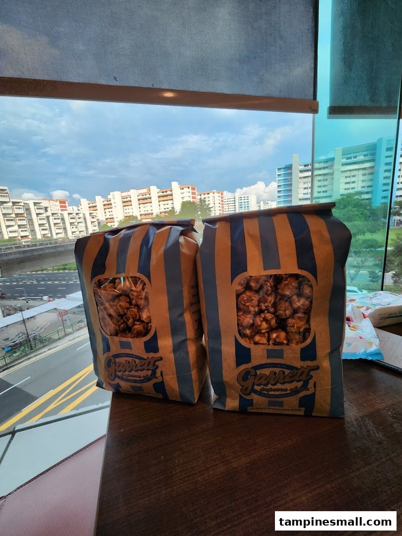 Two bags of Garrett Popcorn on a table with a city view from a window.