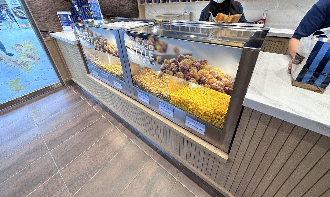 A counter at Garrett Popcorn Shops displaying various popcorn flavors like Chicago Mix and CheeseCorn.