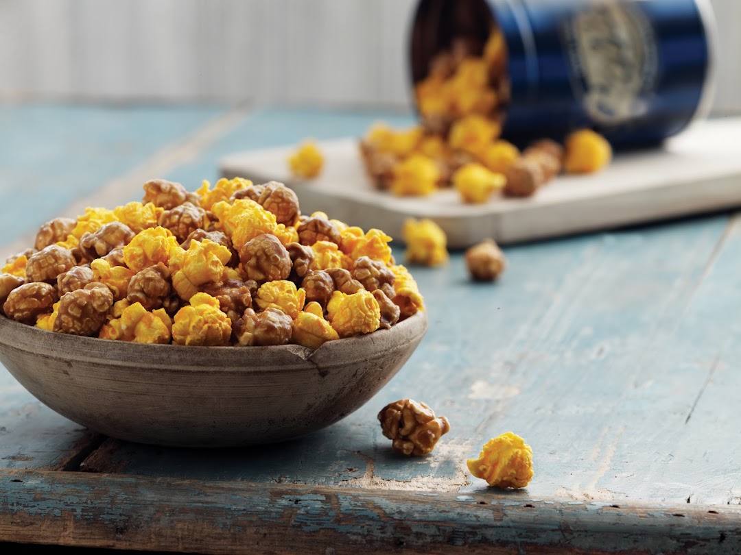 A bowl of Garrett Popcorn's signature Chicago Mix, with more popcorn spilling from a blue tin.