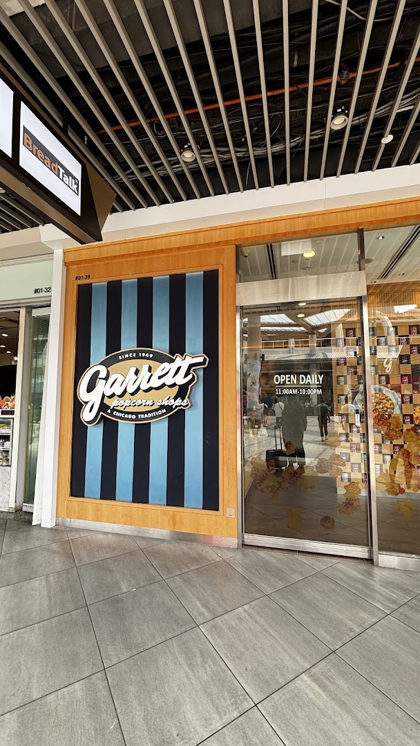 The storefront of Garrett Popcorn Shops featuring its classic striped logo and entrance with operating hours.