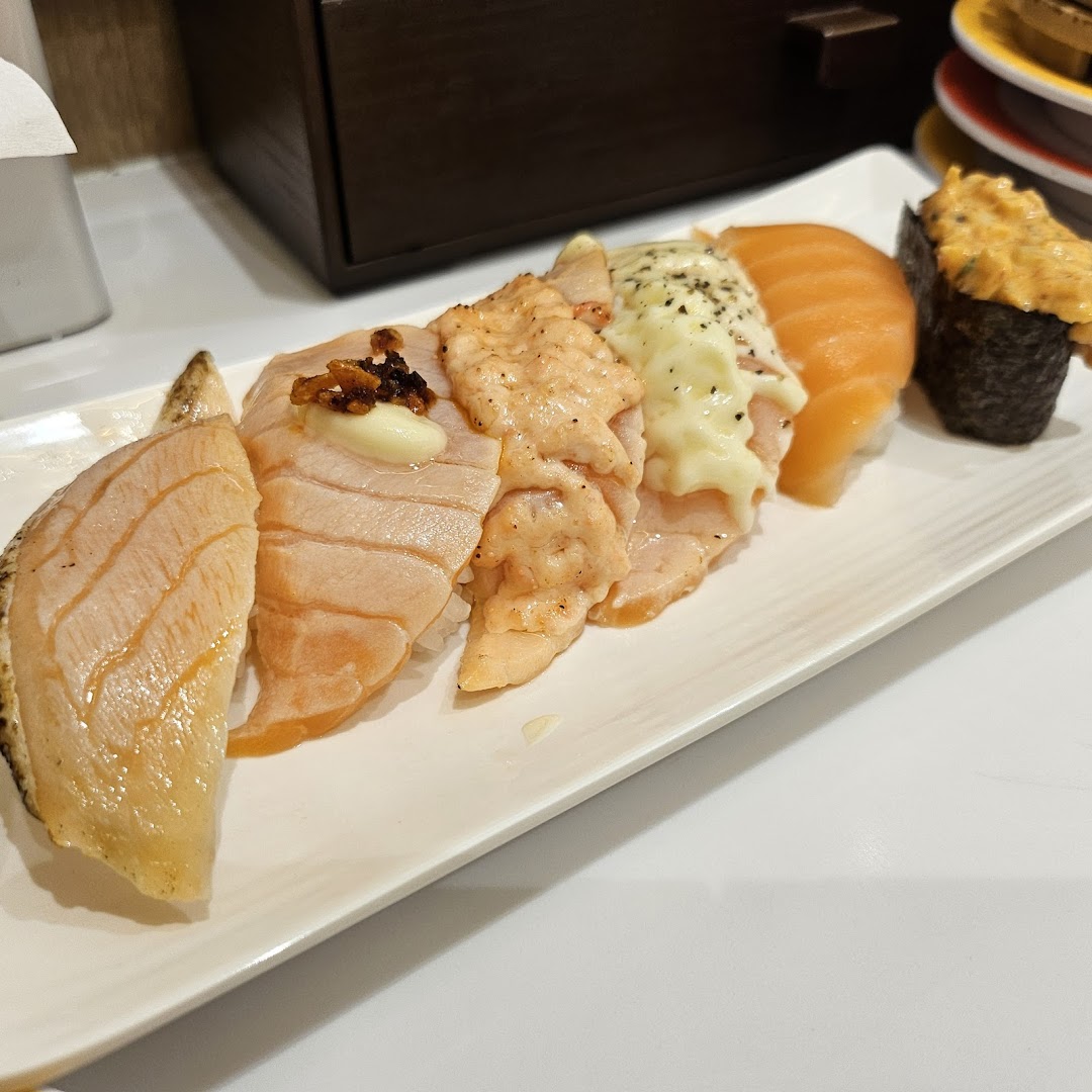 A plate showcasing various salmon sushi creations, including aburi and gunkan, from Genki Sushi.