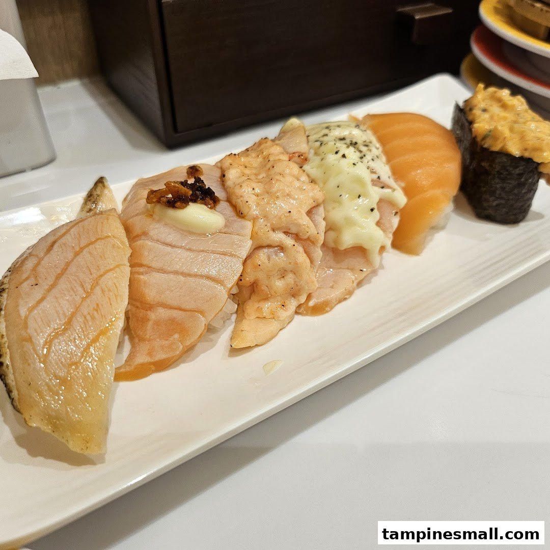 A plate showcasing various salmon sushi creations, including aburi and gunkan, from Genki Sushi.