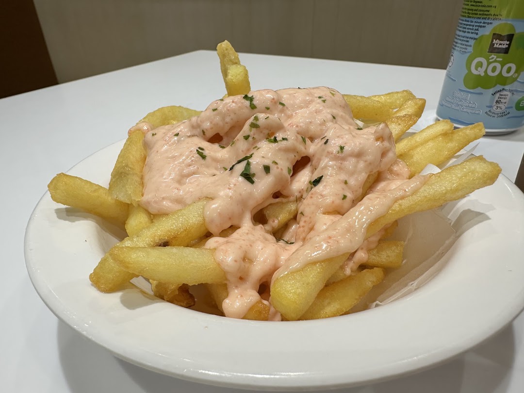 A plate of golden french fries generously topped with a creamy pink sauce and herbs.