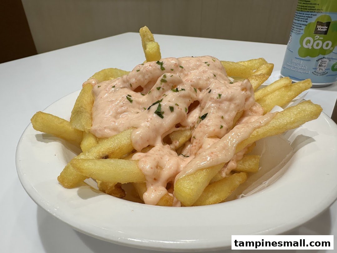 A plate of golden french fries generously topped with a creamy pink sauce and herbs.
