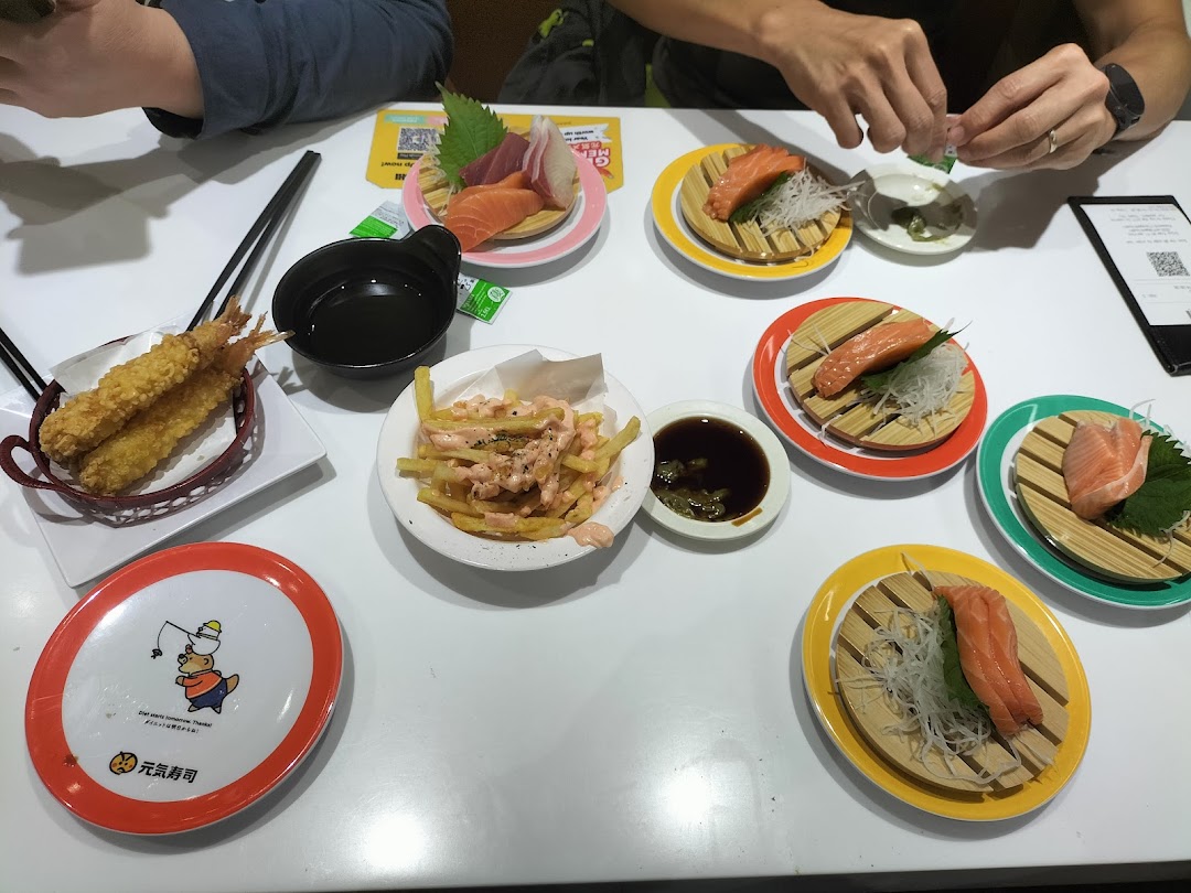 A table laden with fresh sushi, tempura, and fries at Genki Sushi, ready for enjoyment.