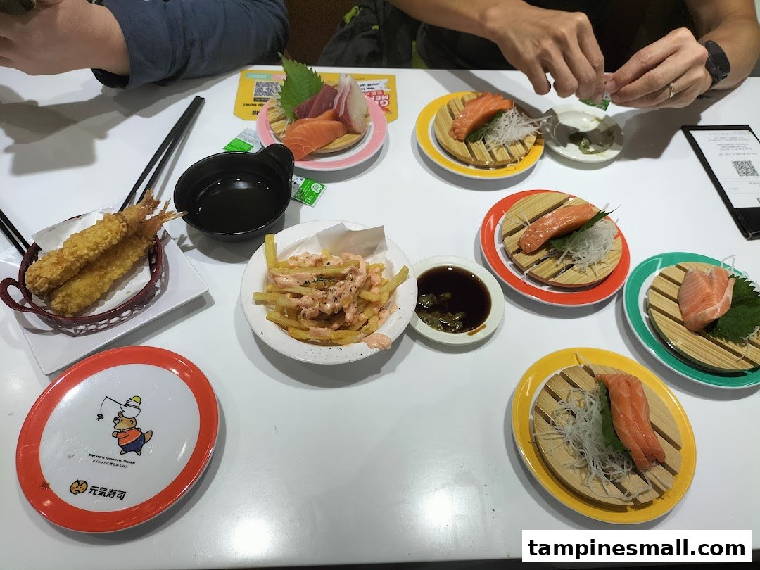 A table laden with fresh sushi, tempura, and fries at Genki Sushi, ready for enjoyment.