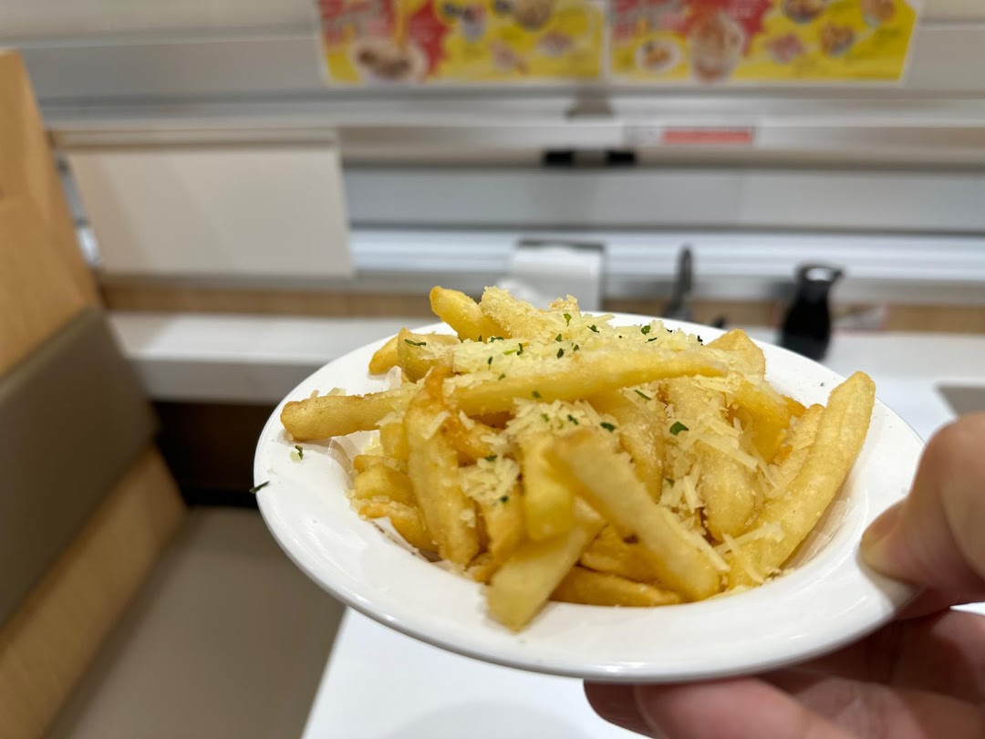 A close-up of crispy french fries topped with grated cheese and herbs, served at Genki Sushi.