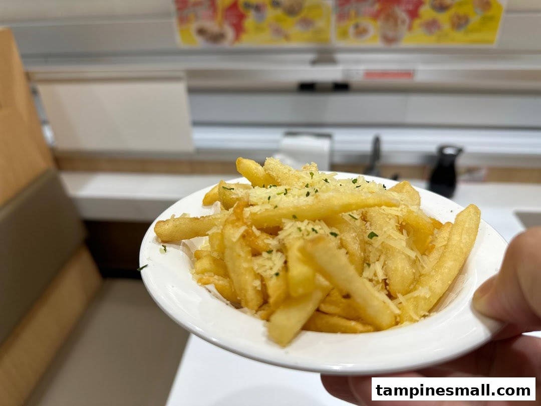 A close-up of crispy french fries topped with grated cheese and herbs, served at Genki Sushi.