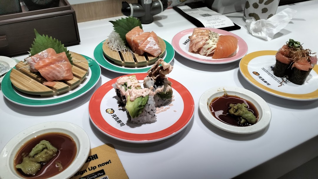 Various fresh sushi and sashimi dishes served on plates at Genki Sushi.