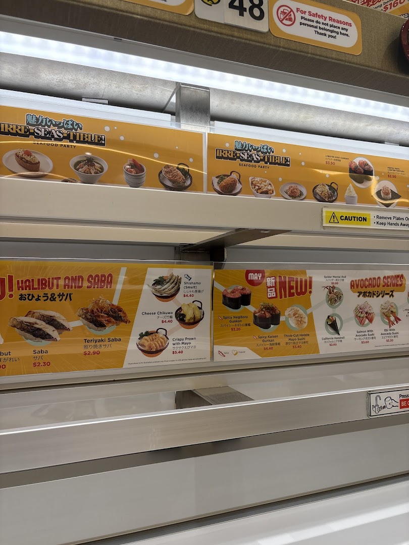 Close-up of Genki Sushi's conveyor belt menu displays featuring various sushi and seafood dishes.