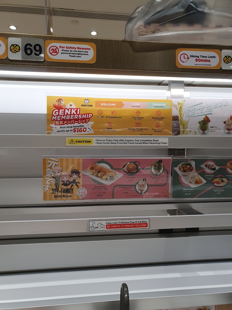 A close-up view of Genki Sushi's conveyor belt system, displaying menu items, promotions, and safety guidelines.