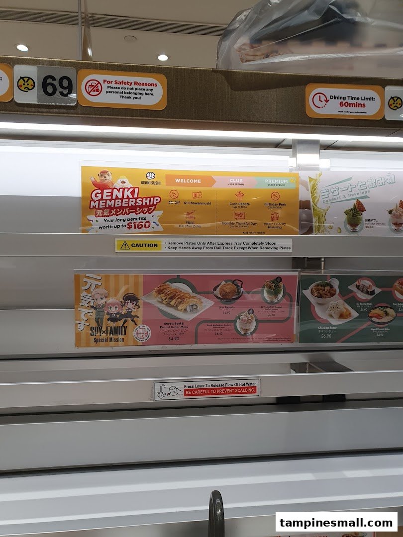 A close-up view of Genki Sushi's conveyor belt system, displaying menu items, promotions, and safety guidelines.