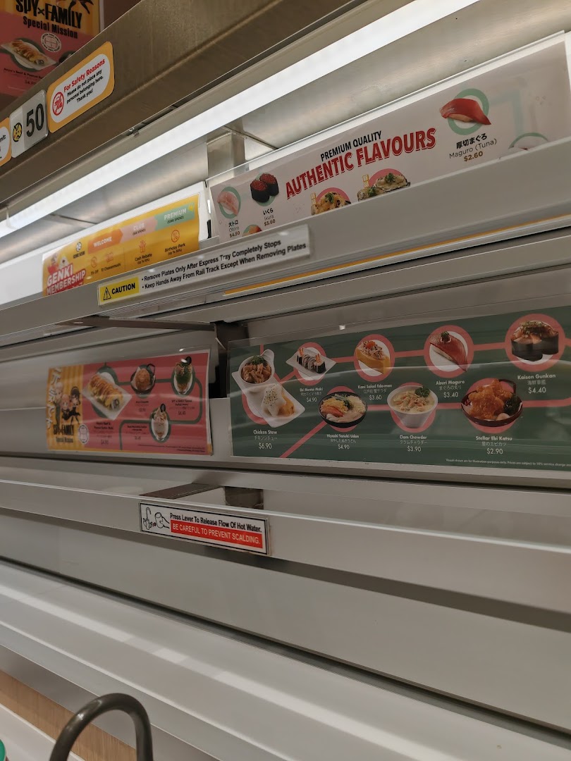 Close-up of a sushi conveyor belt displaying various fresh sushi and hot food items with prices.