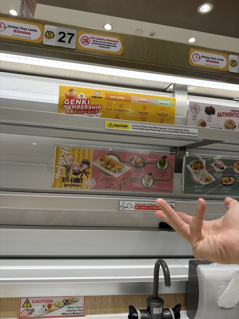 Interior view of Genki Sushi, highlighting the unique express conveyor belt dining system and promotional displays.