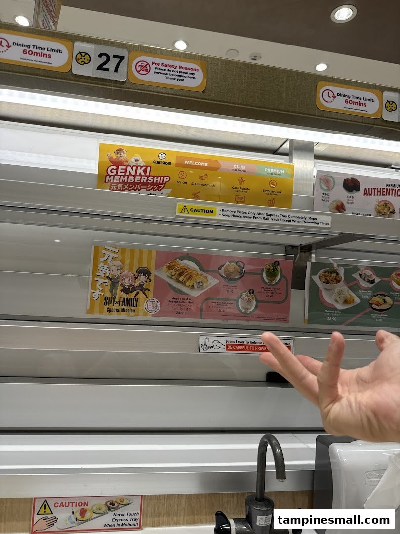 Interior view of Genki Sushi, highlighting the unique express conveyor belt dining system and promotional displays.