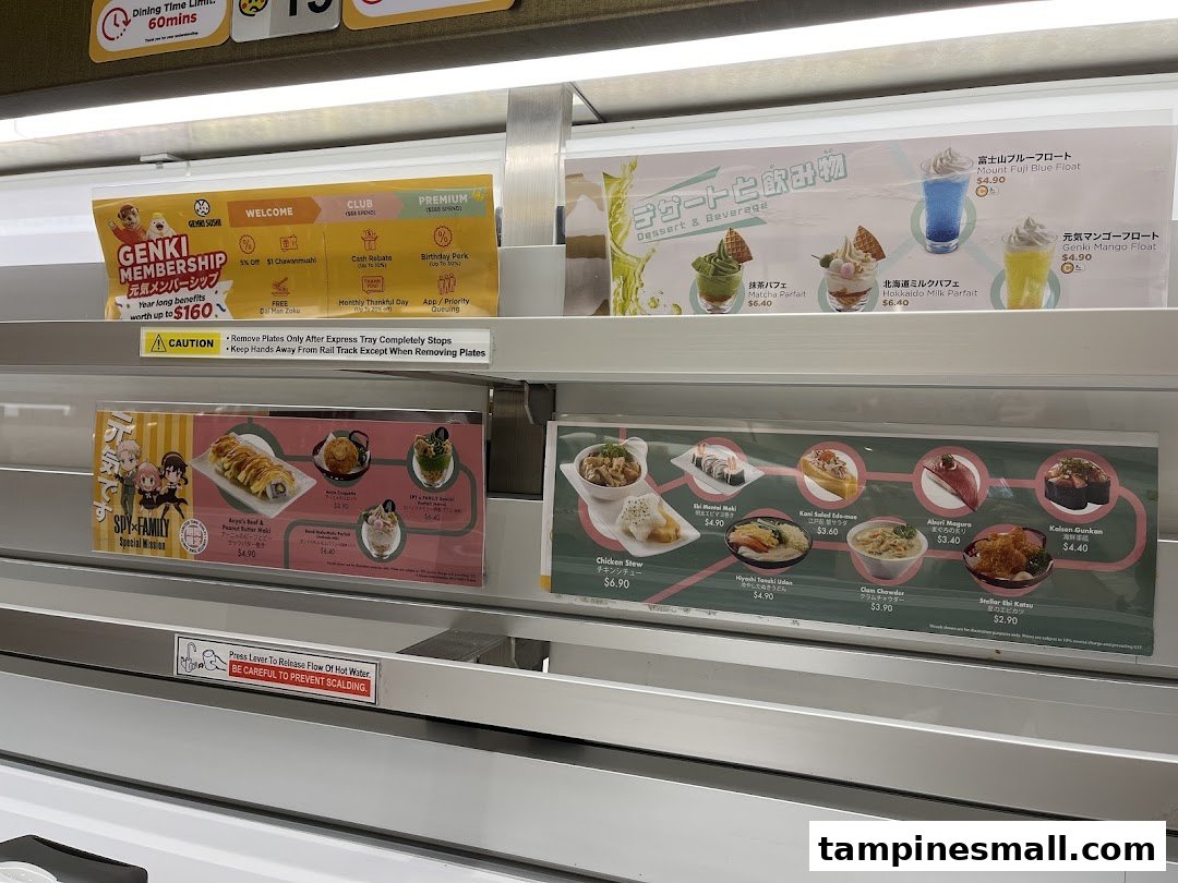 Close-up of Genki Sushi's conveyor belt displaying menu items, desserts, drinks, and membership benefits.
