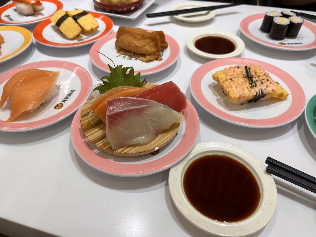 A table laden with various colorful sushi and sashimi dishes on plates at Genki Sushi.