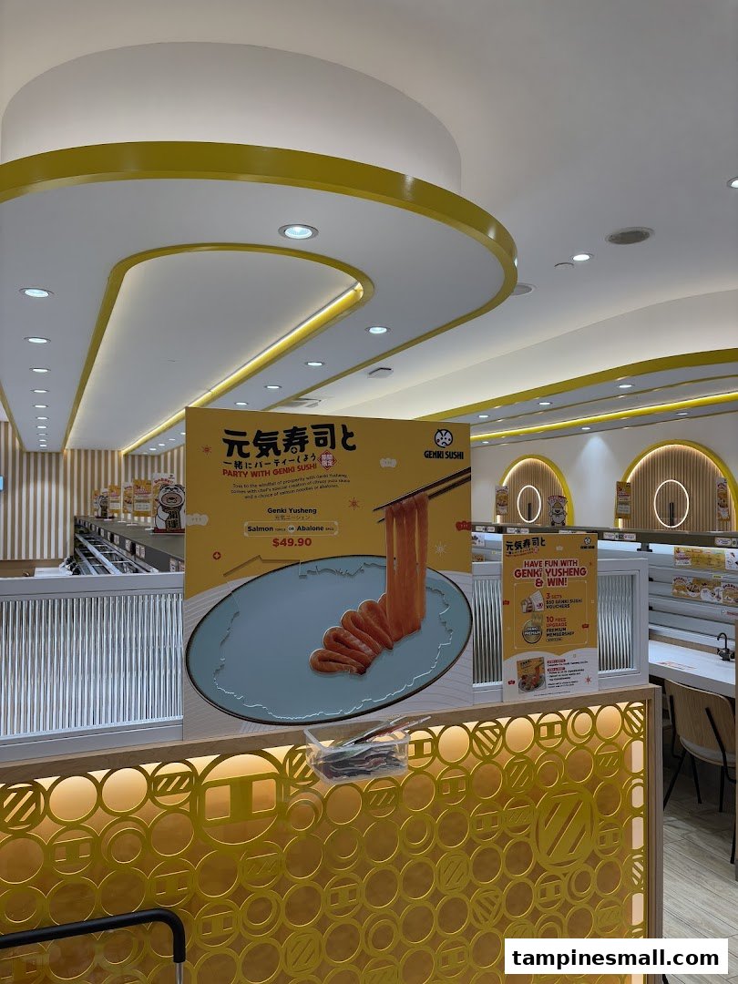 Interior view of Genki Sushi featuring a promotional display for Genki Yusheng and the restaurant's conveyor belt system.