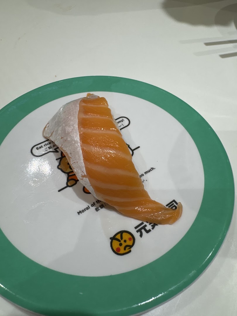 A close-up of a fresh salmon sushi piece on a distinctive Genki Sushi plate.