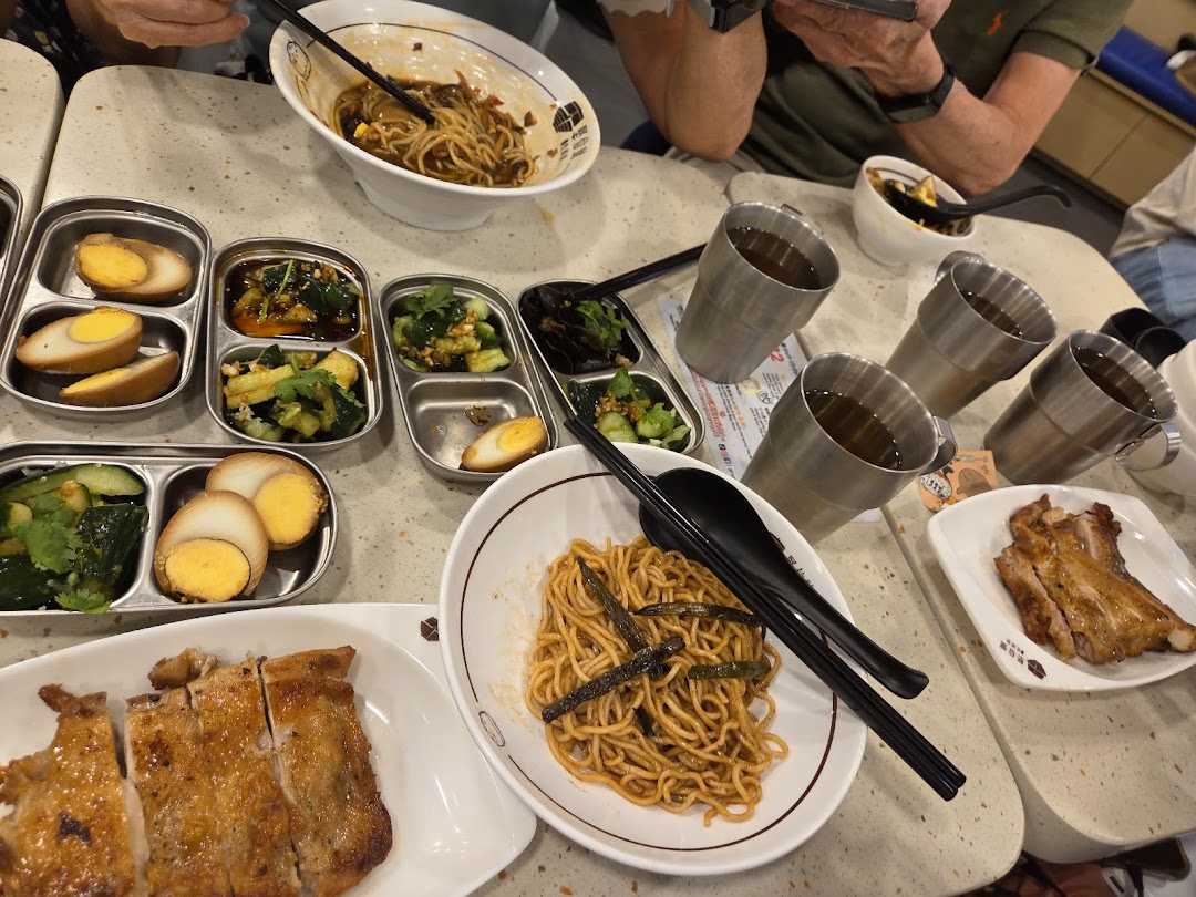A table laden with delicious noodles, roasted chicken, side dishes, and drinks at Ging Sun Ho King of Bun.