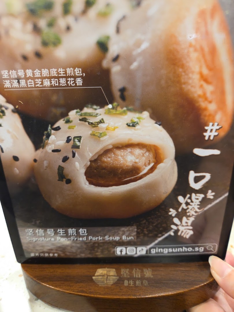 A close-up image of a Signature Pan-Fried Pork Soup Bun on a display stand.