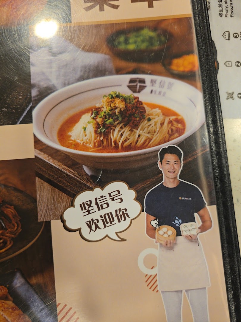 A menu page displaying a bowl of noodles, a cartoon character, and text about buns.