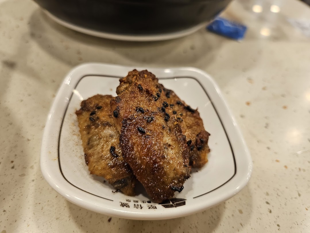 A plate of crispy, seasoned chicken wings with black sesame seeds on a white dish.