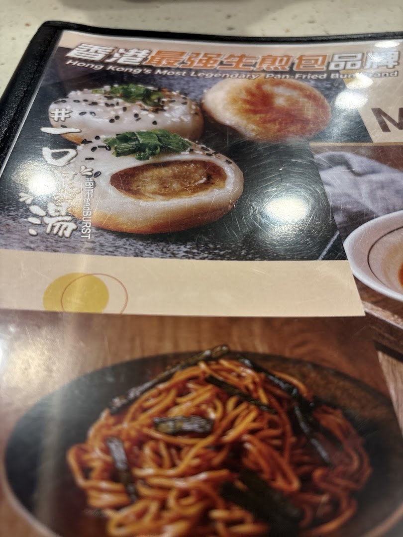A close-up of a menu page featuring pan-fried buns described as 'Hong Kong's Most Legendary' and a dish of noodles.
