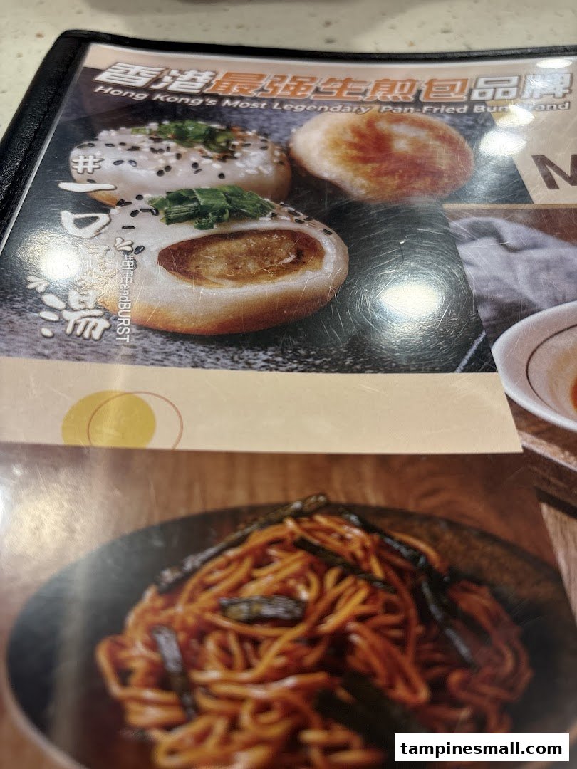 A close-up of a menu page featuring pan-fried buns described as 'Hong Kong's Most Legendary' and a dish of noodles.