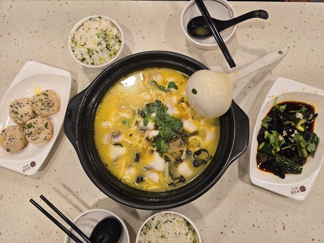 A vibrant overhead shot of delicious Chinese dishes, including fish soup, pan-fried buns, and sides.