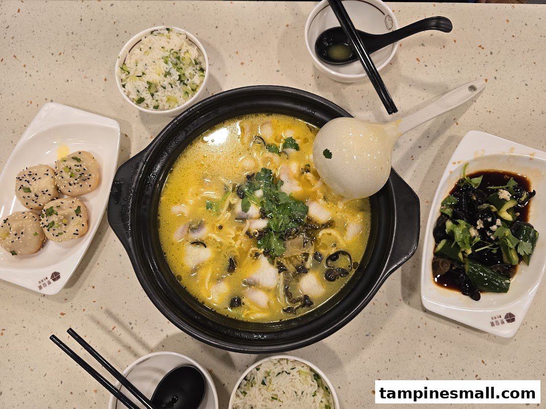 A vibrant overhead shot of delicious Chinese dishes, including fish soup, pan-fried buns, and sides.