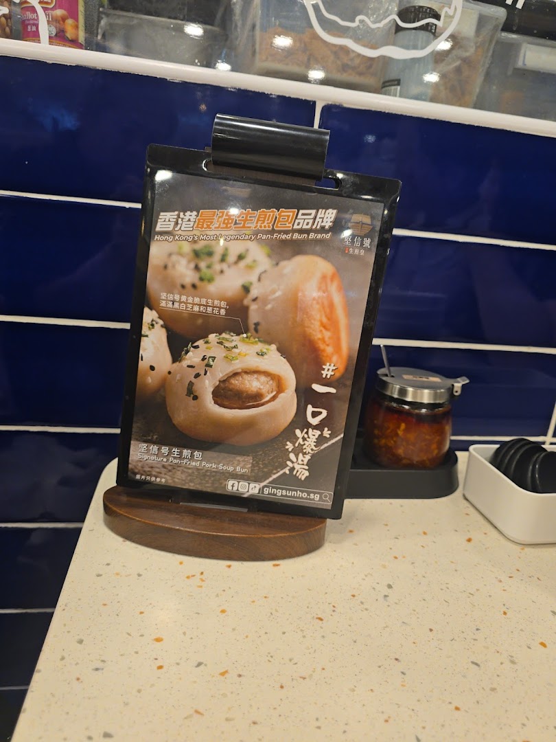 A display stand showcasing the Signature Pan-Fried Pork Soup Bun with descriptive text.