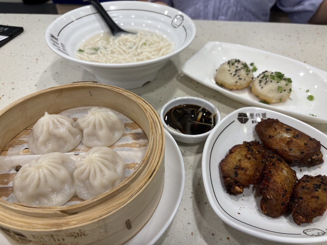 A table spread with delicious Chinese dishes including noodles, dumplings, and fried wings.