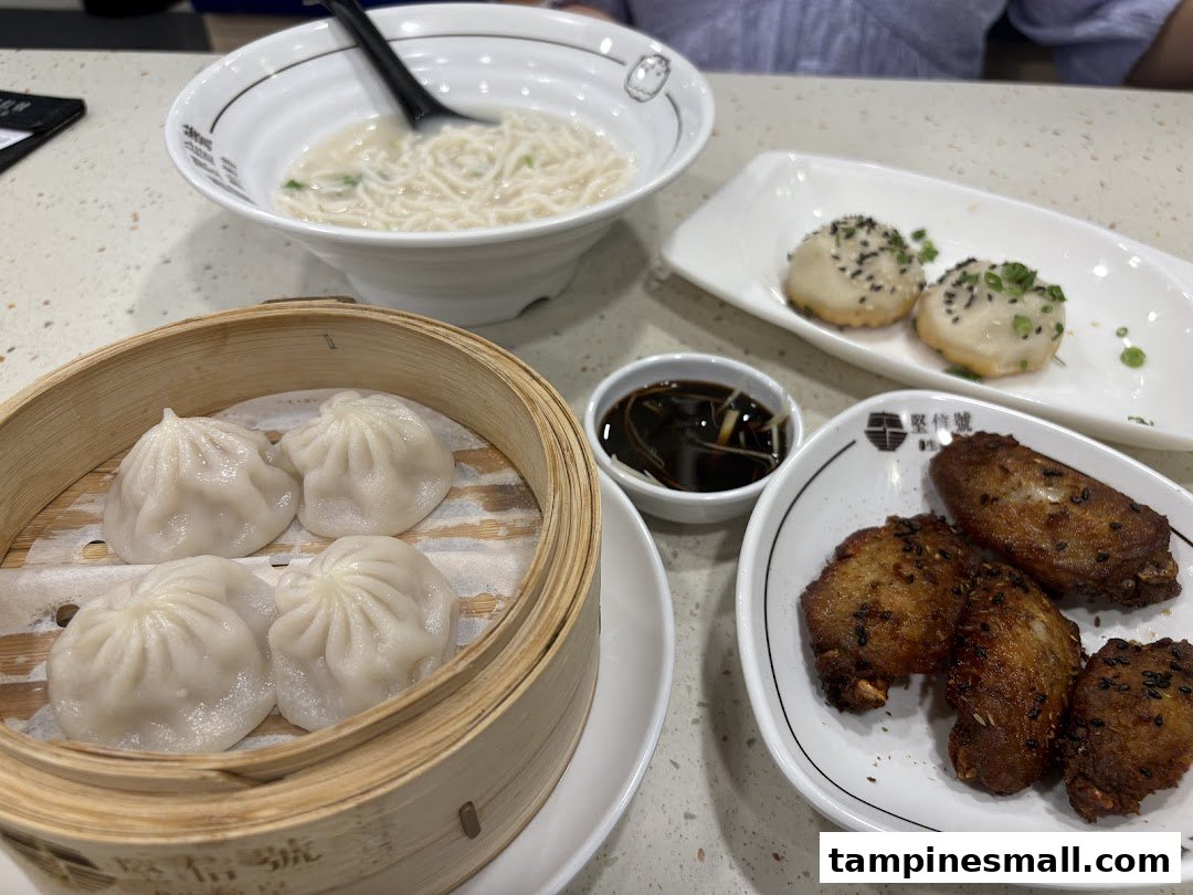 A table spread with delicious Chinese dishes including noodles, dumplings, and fried wings.