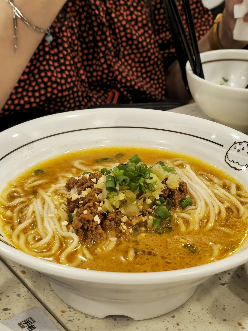 A close-up of a delicious bowl of noodles with minced meat and green onions.