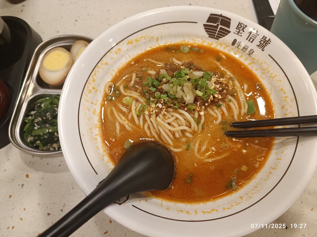A vibrant bowl of spicy noodles with minced meat and green onions, accompanied by side dishes.