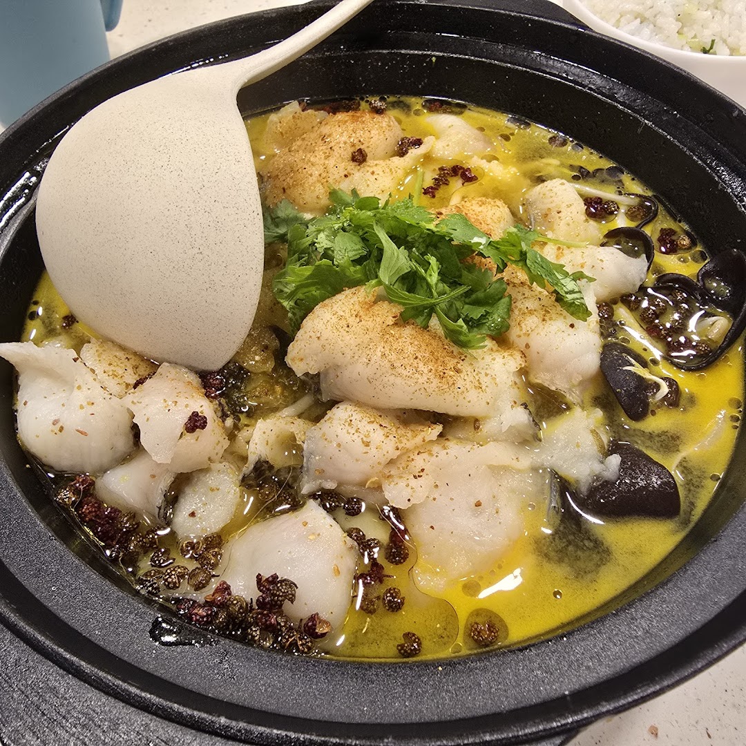 A vibrant hot pot dish featuring tender fish fillets, spices, and fresh cilantro.