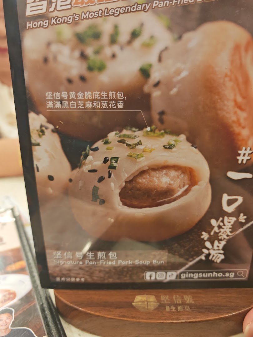 Close-up of a menu display featuring a Signature Pan-Fried Pork Soup Bun with sesame and spring onions.