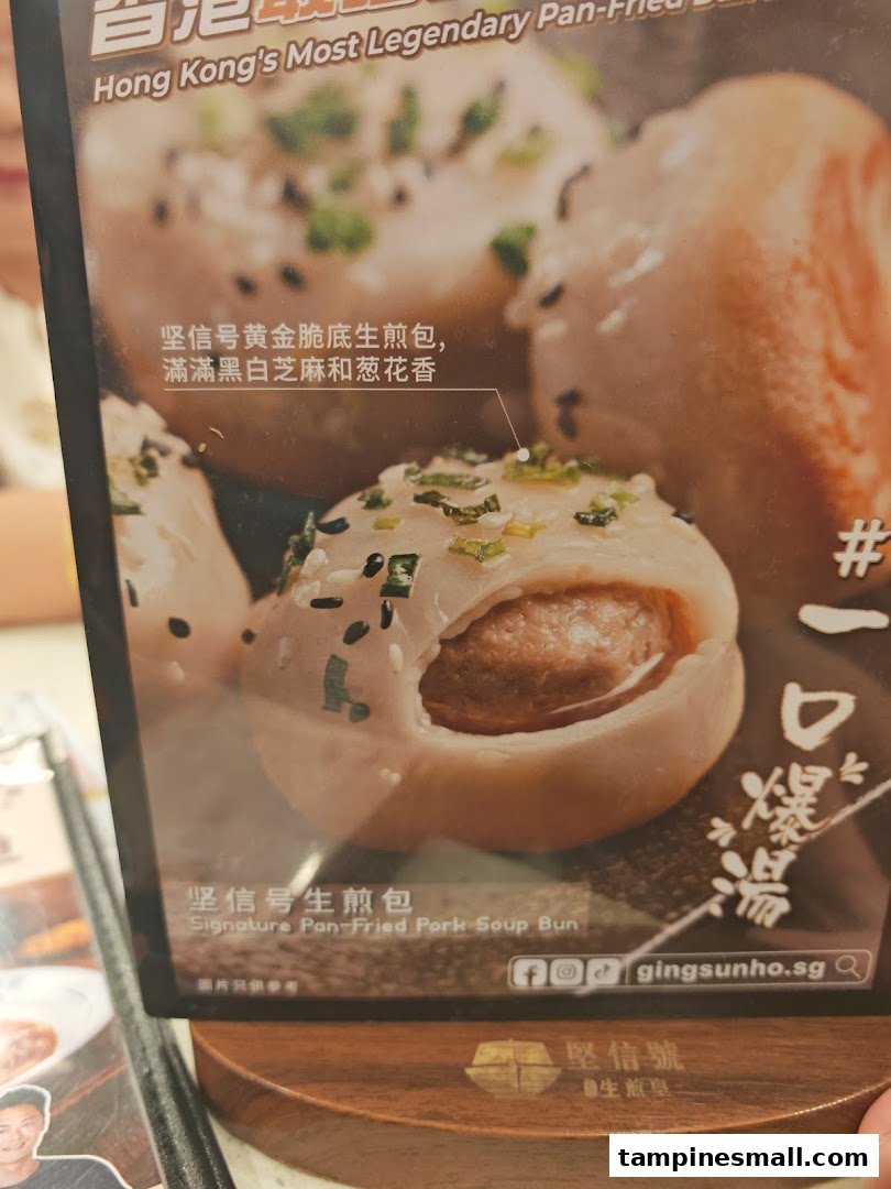 Close-up of a menu display featuring a Signature Pan-Fried Pork Soup Bun with sesame and spring onions.