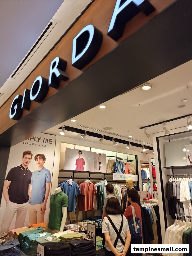 The Giordano shop entrance features its prominent logo, mannequins, and customers browsing a wide selection of apparel.