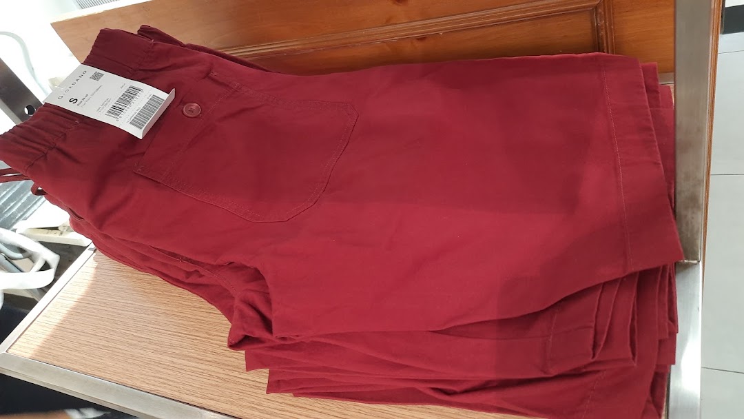 A stack of red casual shorts or pants with a Giordano tag on display in a retail store.